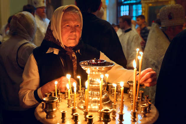 Женщина ставит свечу в церкви